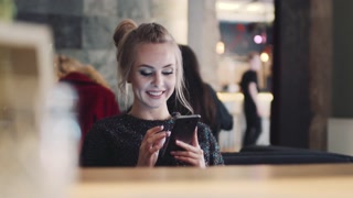 Blonde girl enjoying jokes and memes in a café. Virtual reality fun.